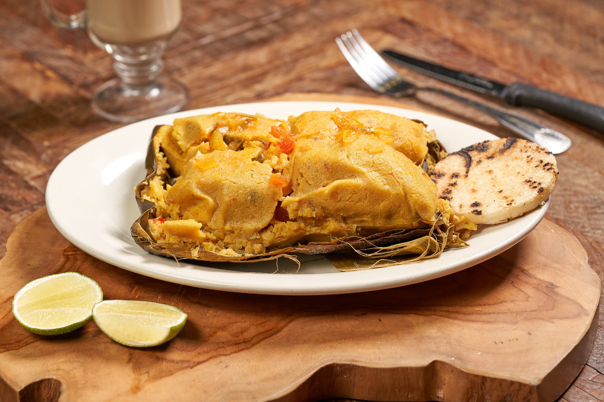 Tamal valluno wrapped in banana leaf served with an arepa